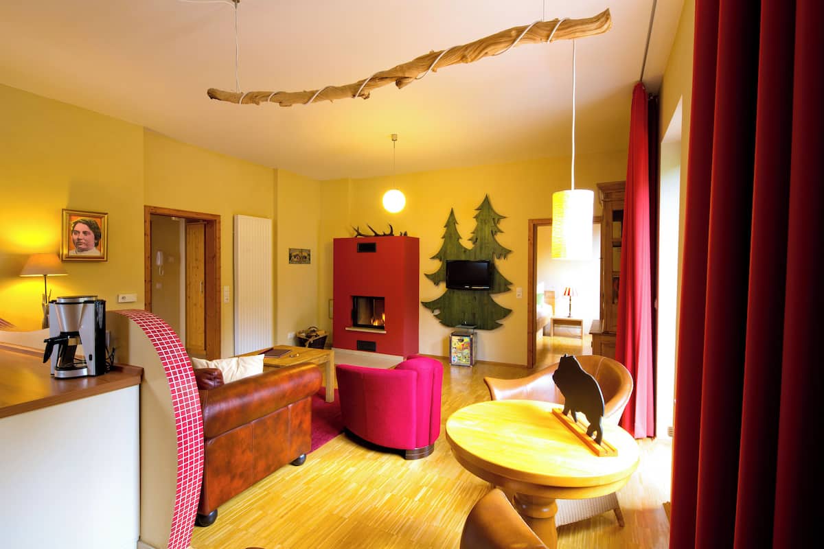 A cozy living room with a red sofa, a wooden coffee table, and a fireplace.