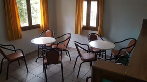 Una habitación con cuatro mesas redondas y seis sillas, dispuestas en forma de cuadrado.
