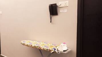 Una tabla de planchar fijada a la pared, un planchador y un teléfono.