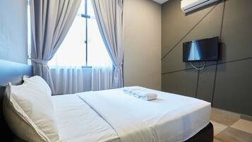 Una habitación de hotel con cama, cortinas, un equipo de aire acondicionado y una televisión.