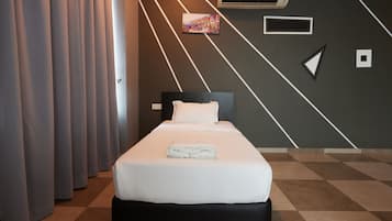 Habitación de hotel con cama, cortinas, aire acondicionado, un cuadro y un diseño geométrico en la pared.