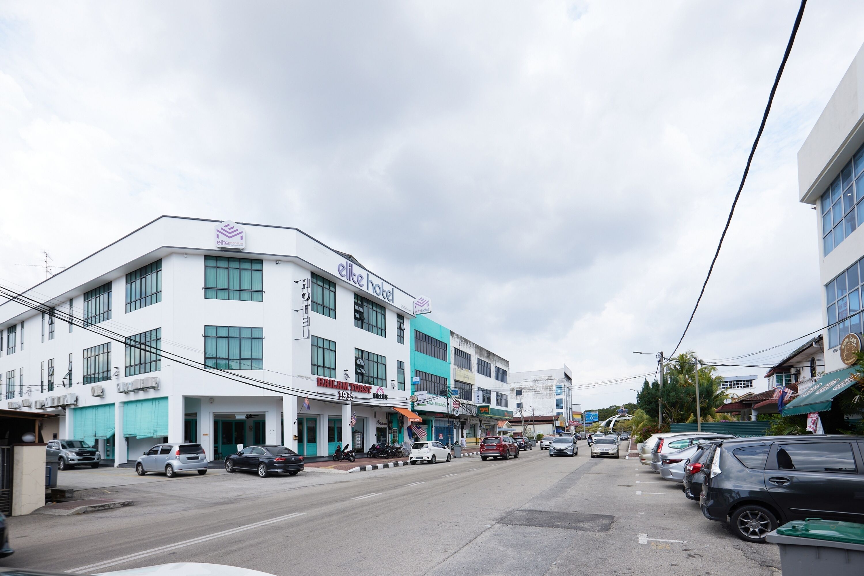 A hotel with a white facade, multiple windows, and a sign indicating it is a hotel.