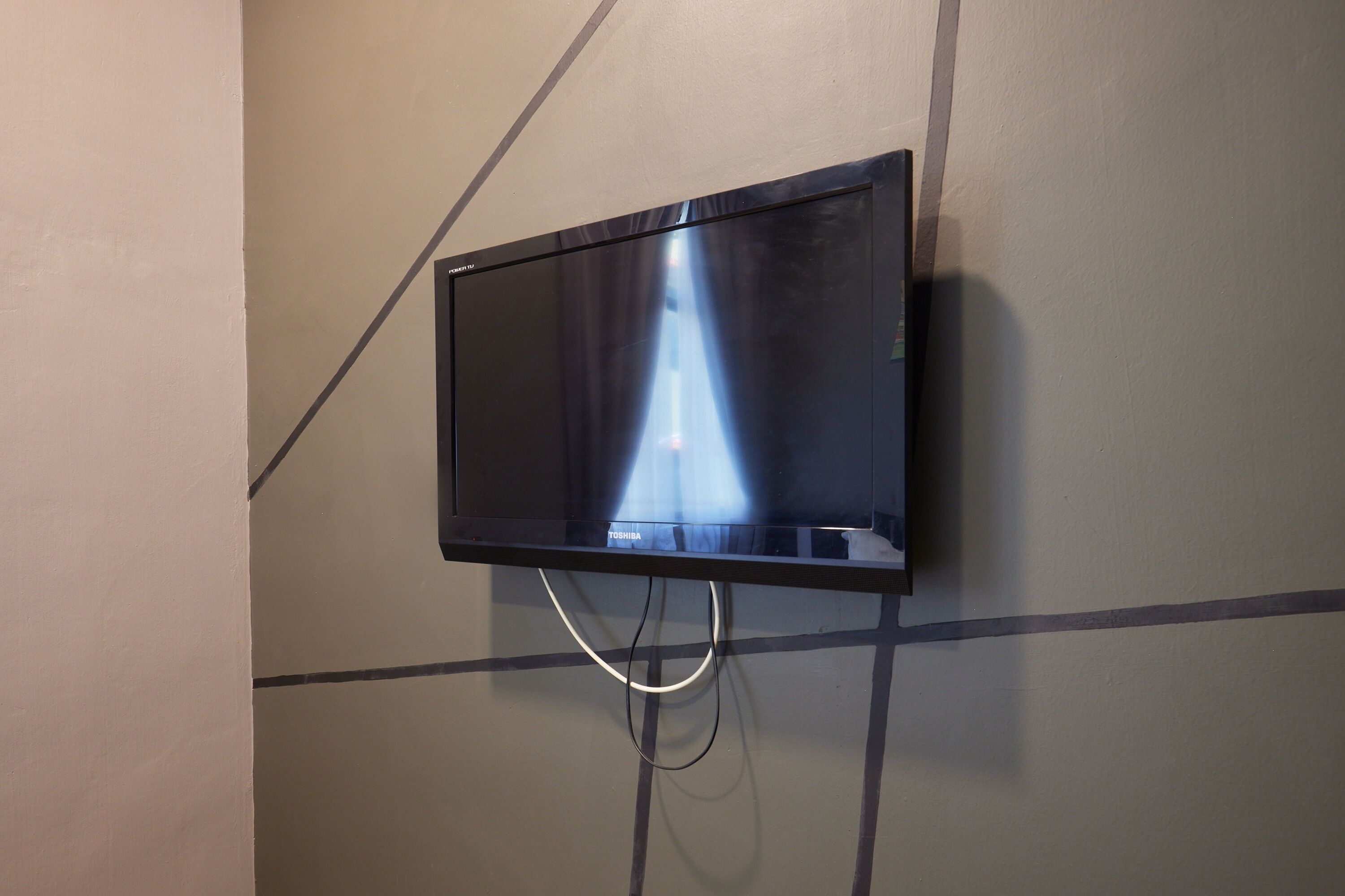 Ein Flachbildfernseher an der Wand befestigt, mit sichtbaren Kabeln.