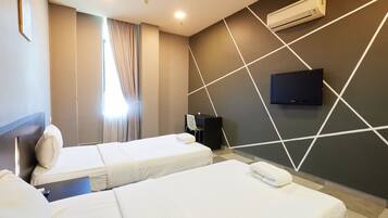 A hotel room with two beds, a flat-screen TV mounted on the wall, and an air conditioning unit.