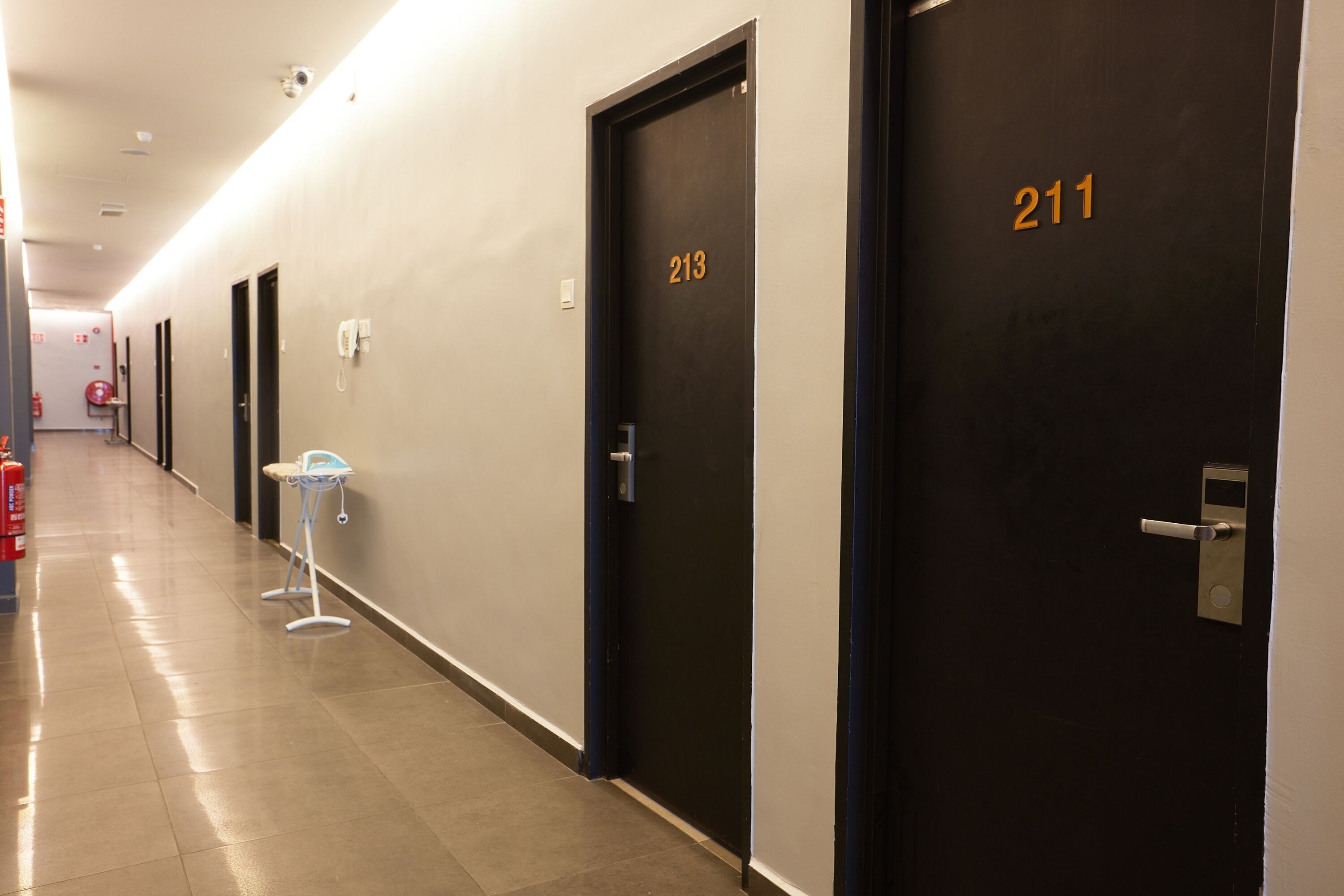 A hotel corridor with doors numbered 213 and 211, a fire extinguisher, and a phone on the wall.