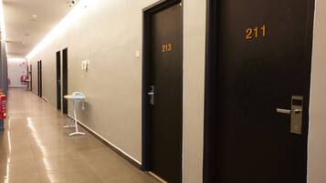 A hotel corridor with doors numbered 213 and 211, a fire extinguisher, and a phone on the wall.