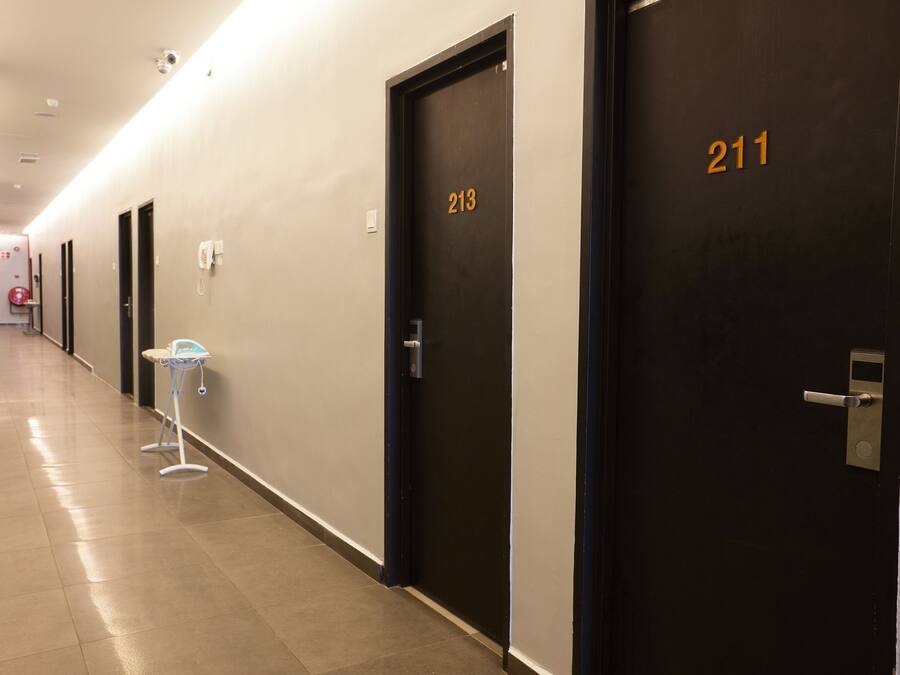 A hotel corridor with doors numbered 213 and 211, a fire extinguisher, and a phone on the wall.
