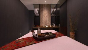 A modern hotel room with a large bed, a wooden accent wall, a small table with a tray, and a potted plant. - Grand Picasso Hotel (Jakarta)