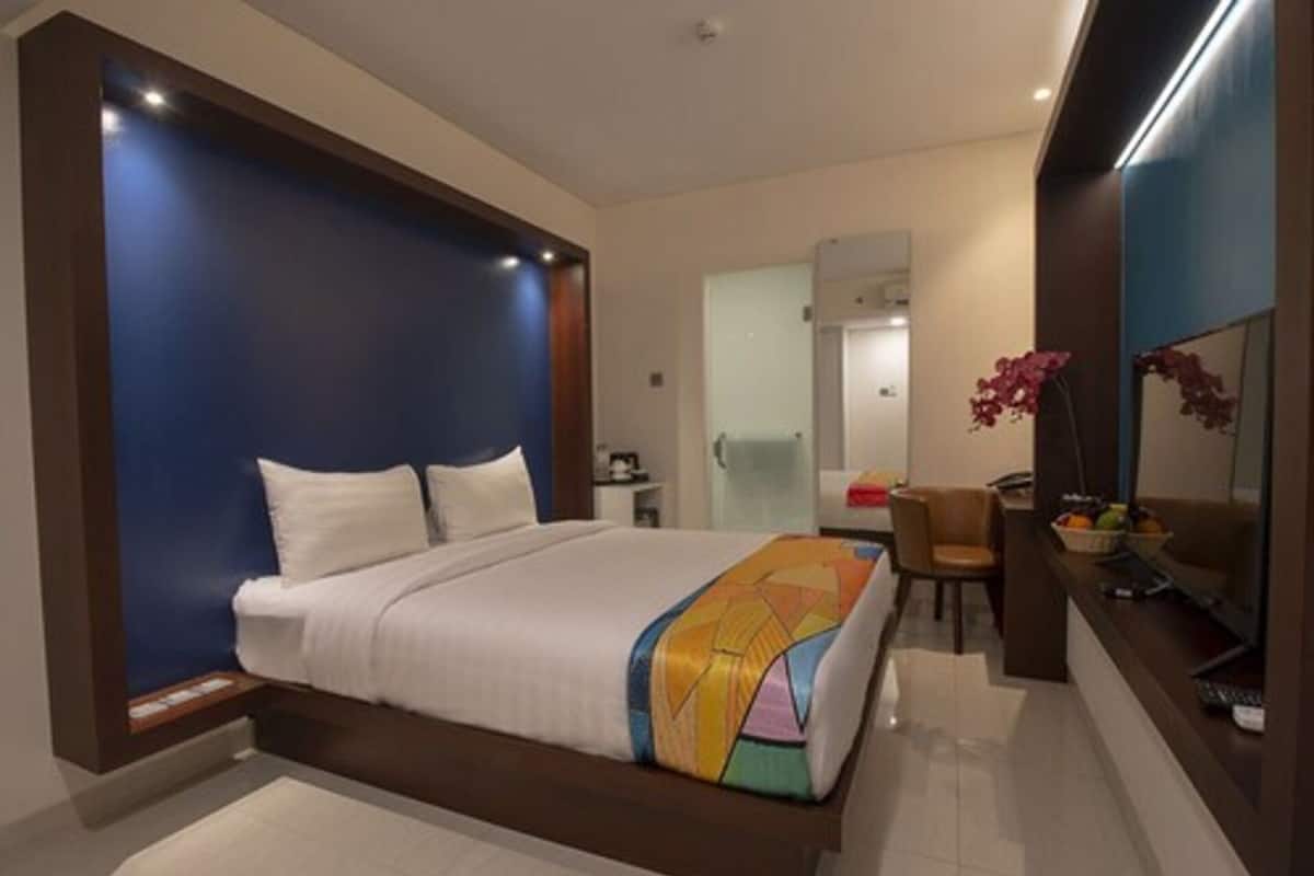 A modern hotel room with a large bed, a desk, and a chair.