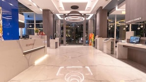 A modern reception area with a marble floor, a reception desk, and a 'Business Corner' sign. - Grand Picasso Hotel (Jakarta)