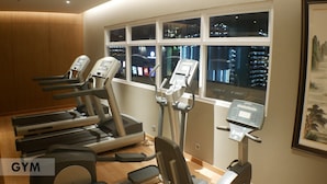 A gym with treadmills and elliptical machines, large windows with a city view, and a framed picture on the wall. - Grand Picasso Hotel (Jakarta)