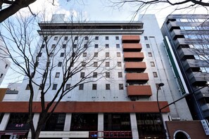 Un immeuble à plusieurs étages, doté d’une façade en briques et de grandes fenêtres.