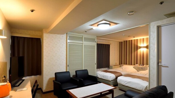 A hotel room with a sofa, two chairs, a small table, a TV, a bed, and a wardrobe. - Hotel Johzenji (Sendai)