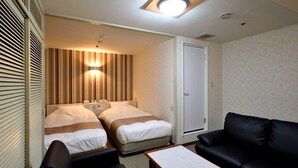 A hotel room with two beds, a black leather sofa, a small table, and a door. - Hotel Johzenji (Sendai)