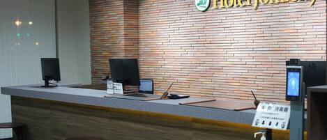 A hotel reception desk with a brick wall, a digital screen, and a sign for Hotel Johzenji.