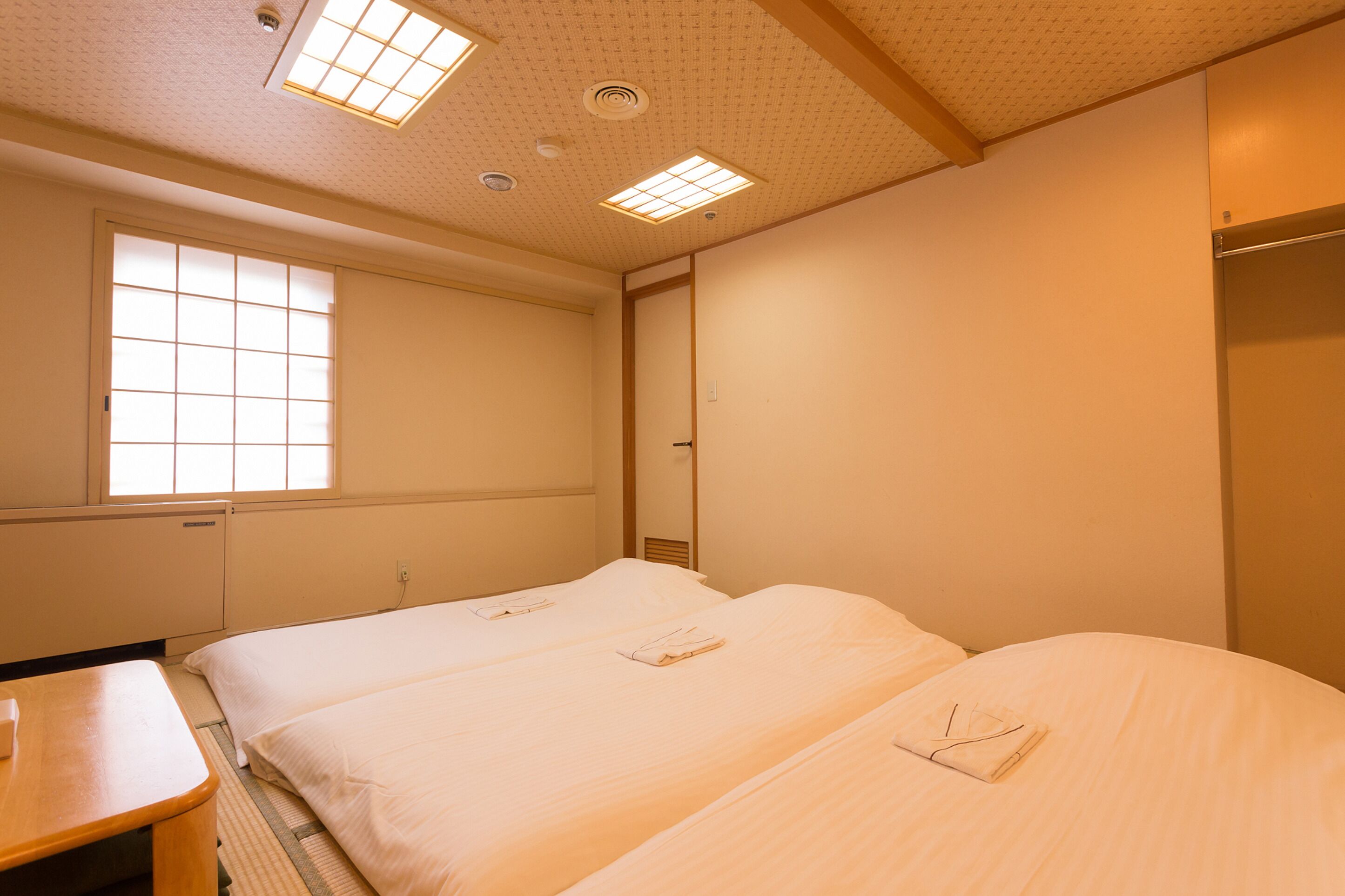 Habitación de hotel con dos camas, una mesita y una ventana con vistas.