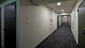 A long, narrow hotel corridor with doors on both sides, a carpeted floor, and a ceiling with recessed lighting. - Hotel Johzenji (Sendai)