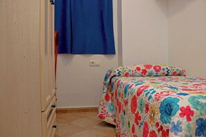 A bedroom with a bed, a wardrobe, and a window with blue curtains.