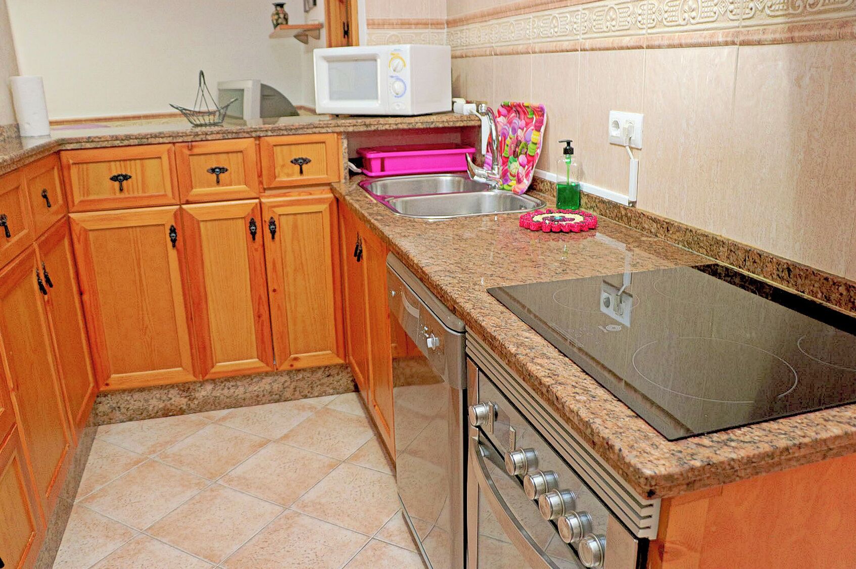 A kitchen with wooden cabinets, a microwave, a sink, and a stove.