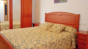 Ein Schlafzimmer mit einem Bett, einem Holzschrank, Nachttischen und einem Wandbild.