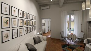 A living room with a sofa, a coffee table, and a rug. There are framed botanical prints on the wall. - Casa Thiele alla Signoria (Florence)