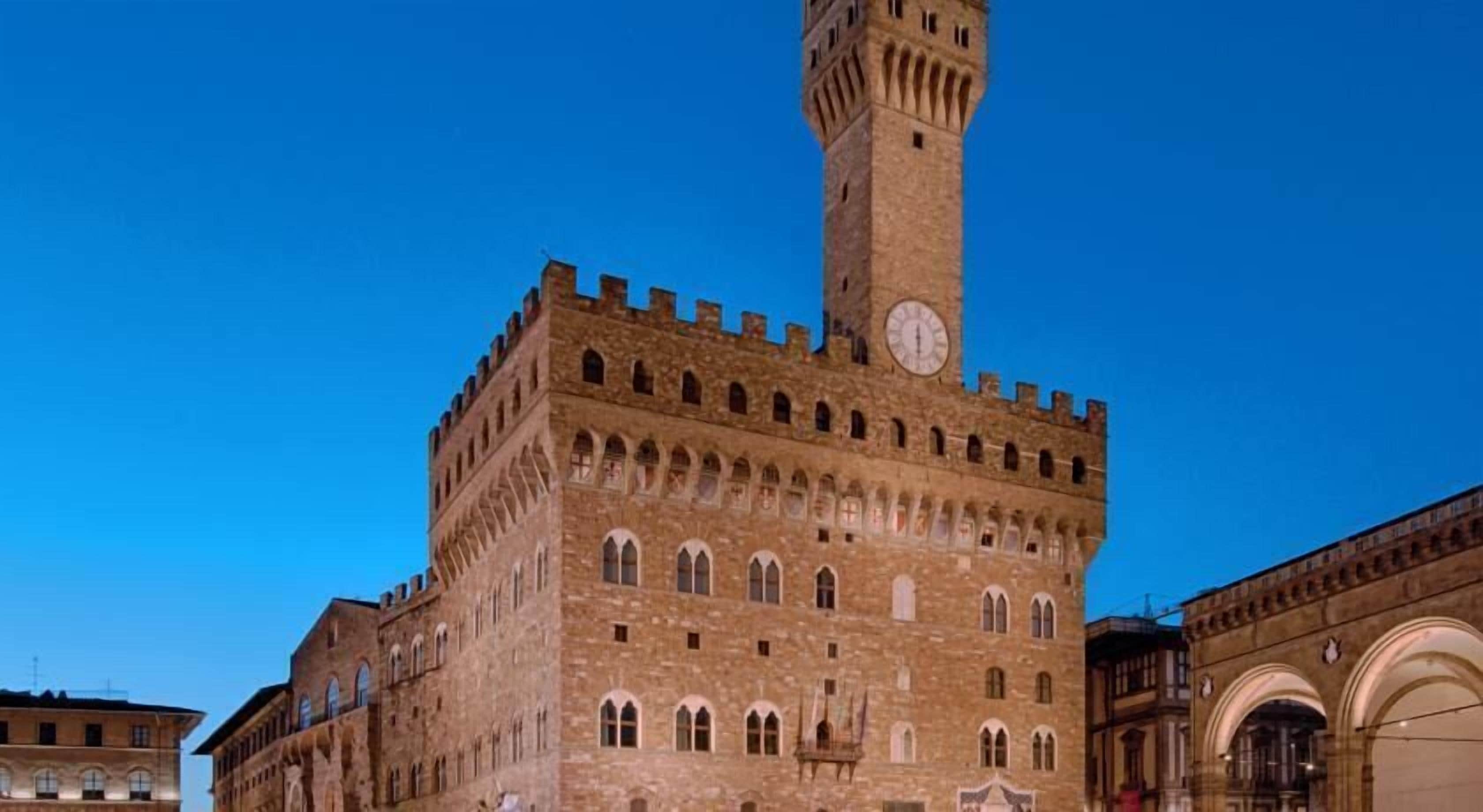A historic building with a prominent clock tower, arched windows, and a fortified appearance.