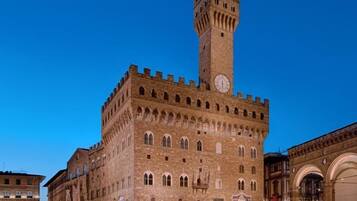 A historic building with a prominent clock tower, arched windows, and a fortified appearance.