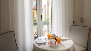 A small balcony with a table set for breakfast, featuring plates, cups, and orange juice. - Casa Thiele alla Signoria (Florence)