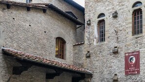 A stone building with a tiled roof and arched windows. A red banner with text is visible on the right side. - Casa Thiele alla Signoria (Florence)