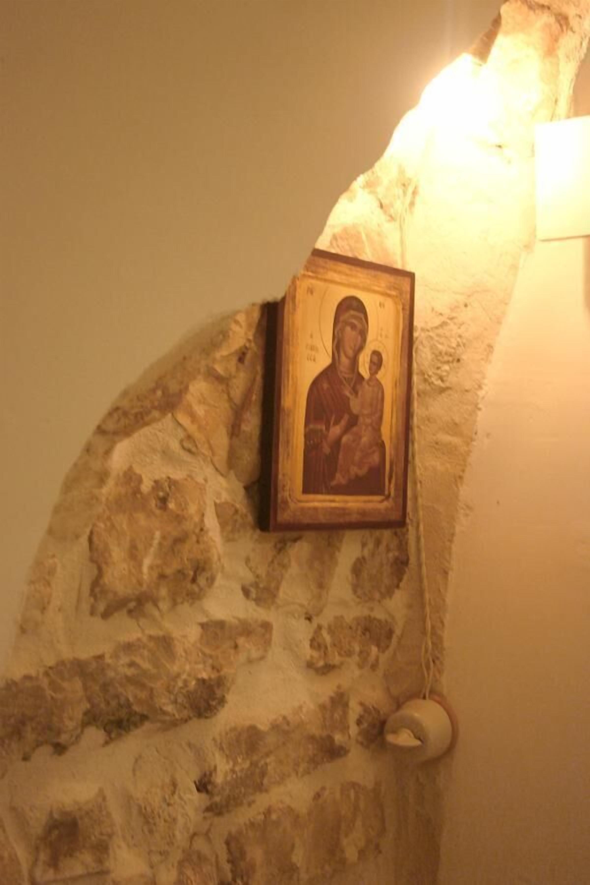 A stone wall with a framed icon hanging on it.