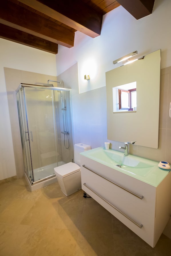 A modern bathroom with a glass-enclosed shower, a white vanity with a mirror, and a light-colored floor. - Domus Hyblaea (Palazzolo Acreide)