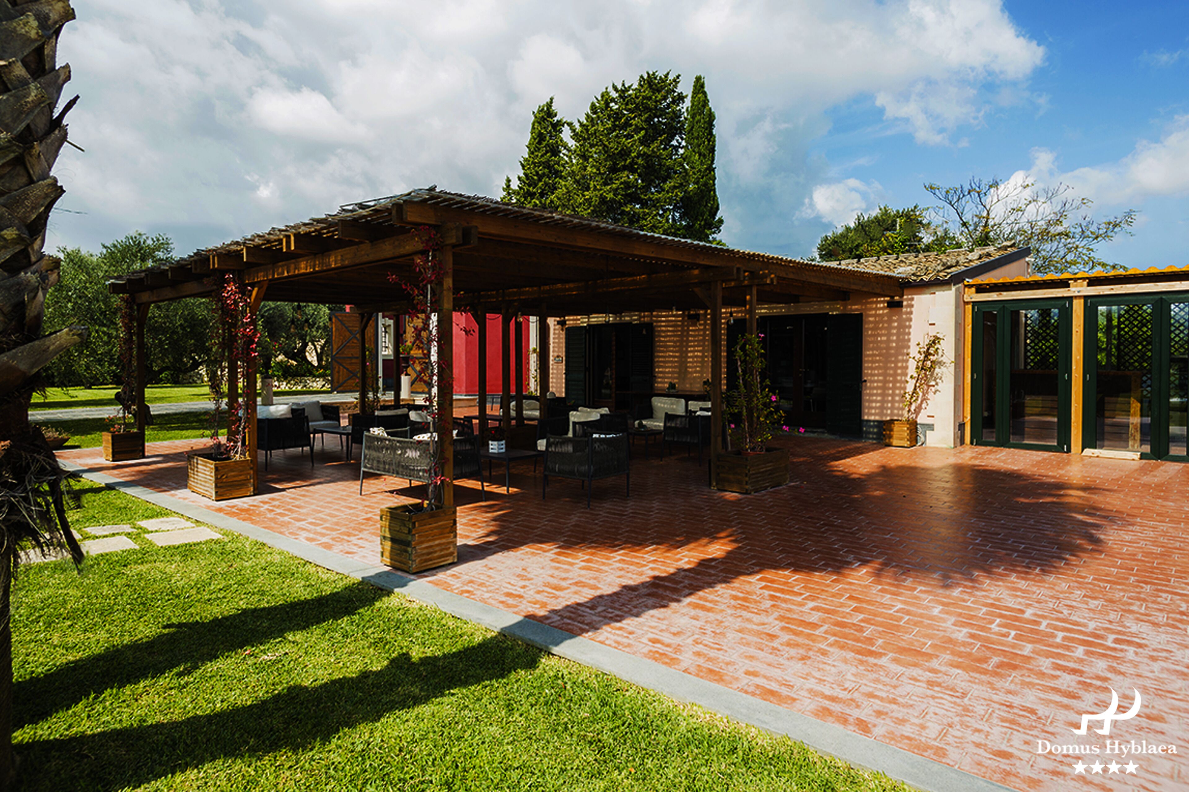 A covered patio with outdoor seating, a brick patio, and a building with large windows.
