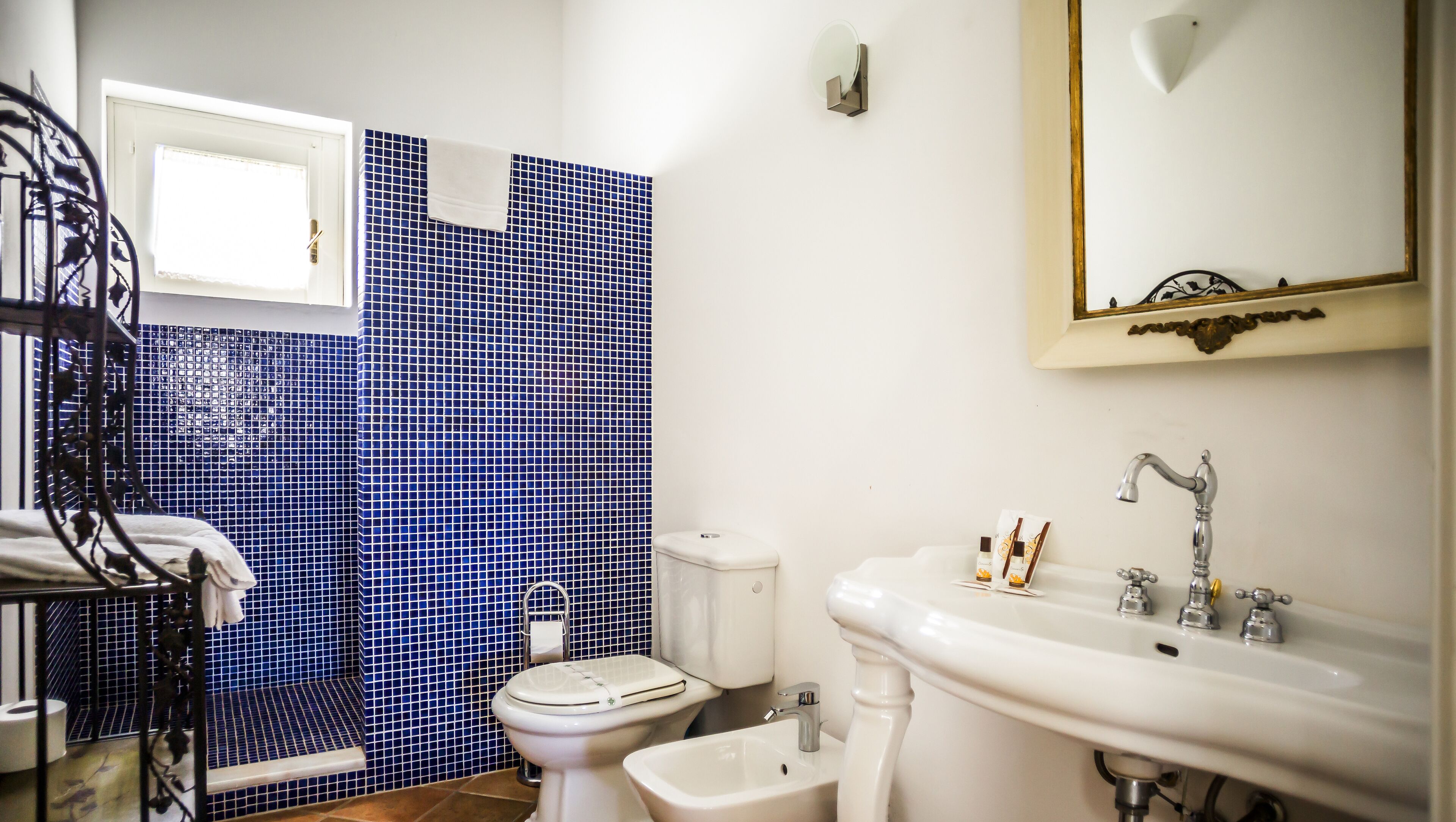 Een badkamer met toilet, wastafel en een blauwe betegelde muur.