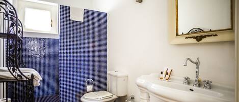 Een badkamer met toilet, wastafel en een blauwe betegelde muur.