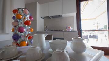 A kitchen with white cabinets, a window with a view of the outside, and a tray with white teacups and a pitcher.