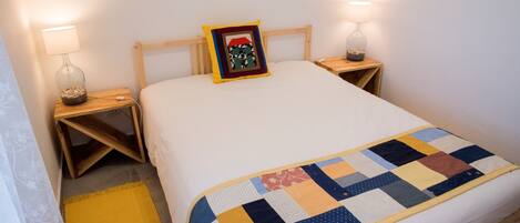 A neatly made bed with a colorful quilt, two bedside lamps, and a small decorative item on the nightstand.