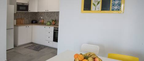 A modern kitchen with white cabinets, a microwave, and a dining area with a table and chairs.