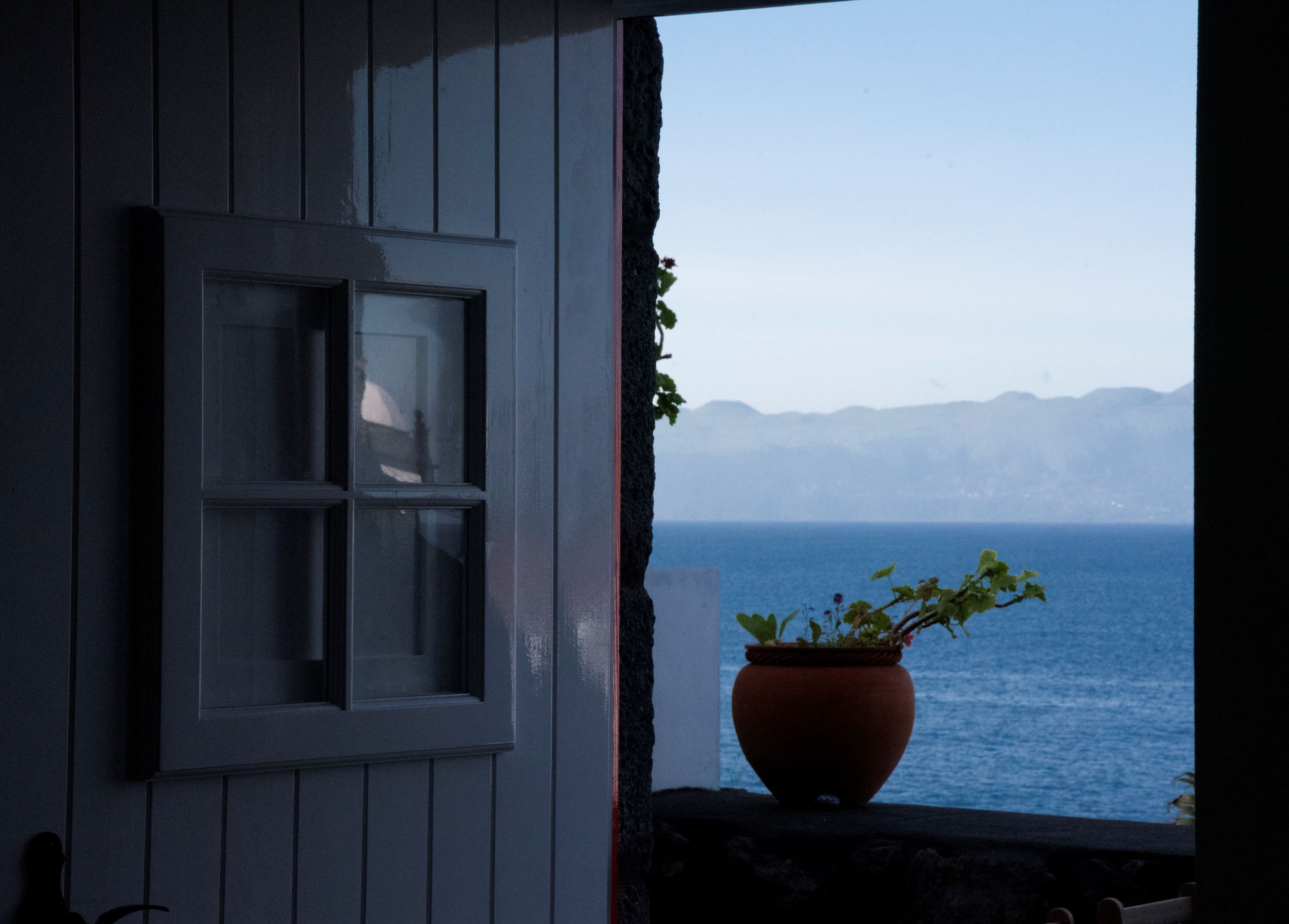 A window with a view of the sea and mountains.