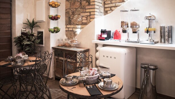 A cozy dining area with a rustic brick wall, a white refrigerator, and a coffee station with various coffee makers and jars. - Lighthouse Suites Trastevere (Rome)