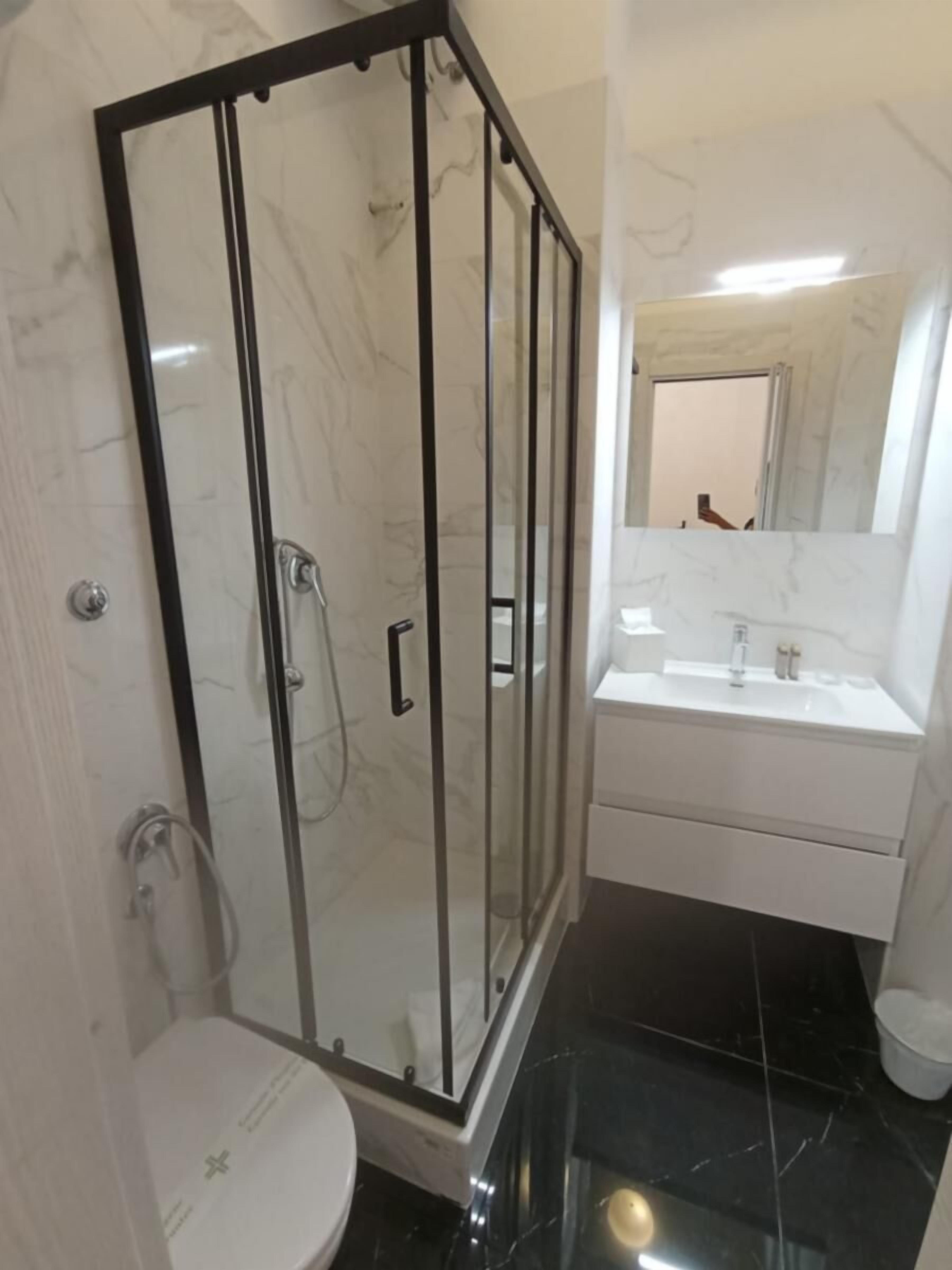 Ein modernes Badezimmer mit einer begehbaren Glasdusche, einem weißen Waschbecken und einer Toilette.
