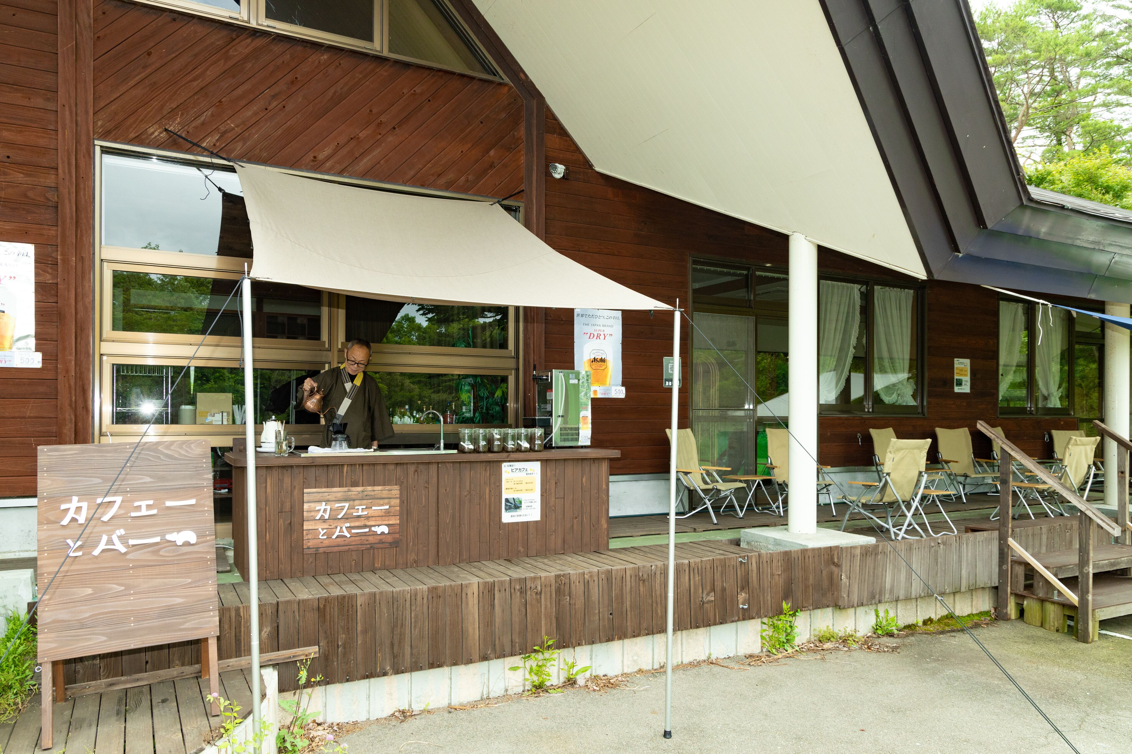 A wooden building with a covered outdoor seating area and a signboard.