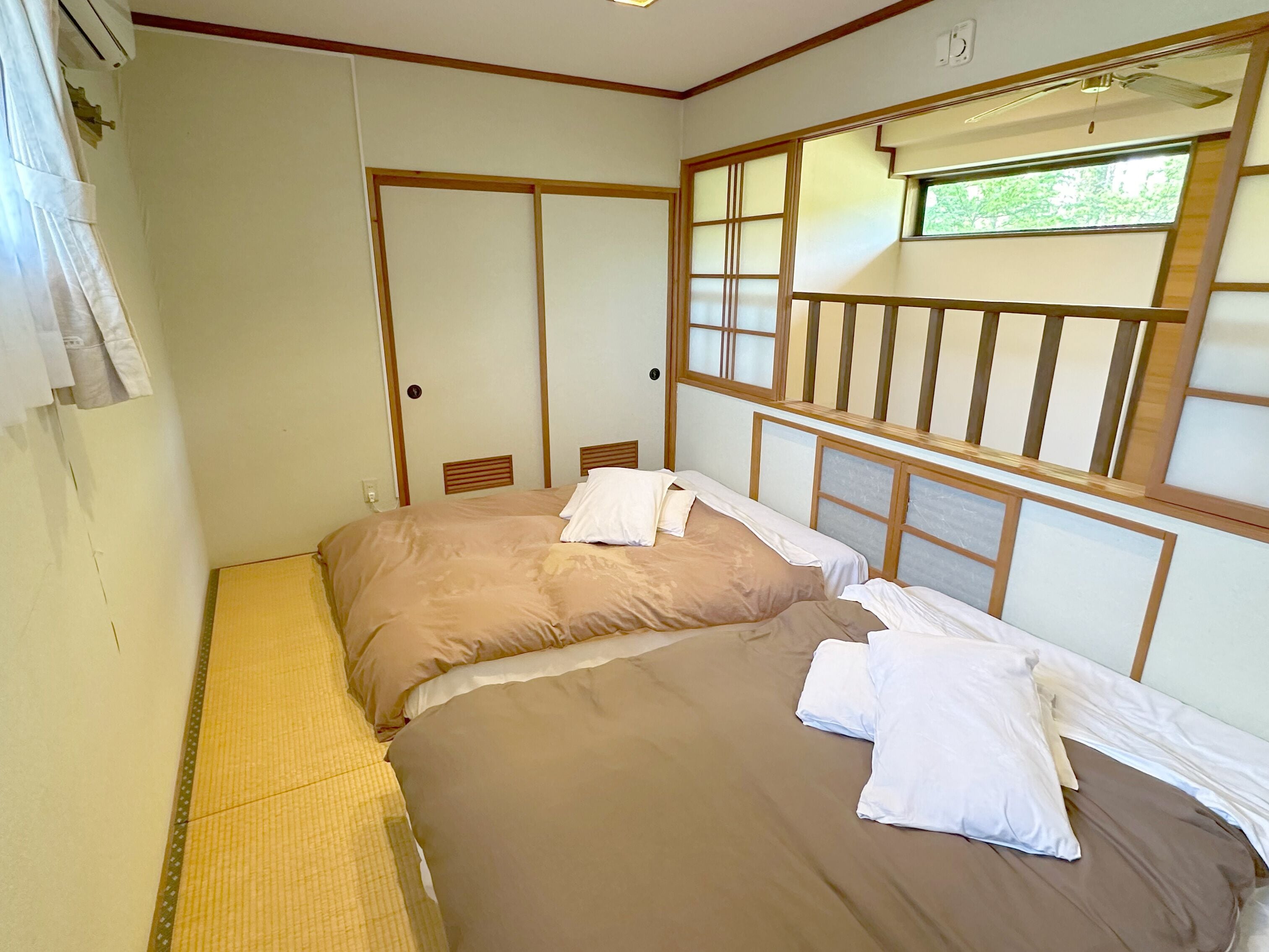 Une chambre avec deux lits, une fenêtre donnant sur un beau paysage et une porte coulissante.
