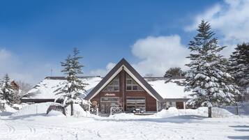 Un alojamiento cubierto de nieve con un techo triangular llamativo y un letrero que dice "Alpenglow".