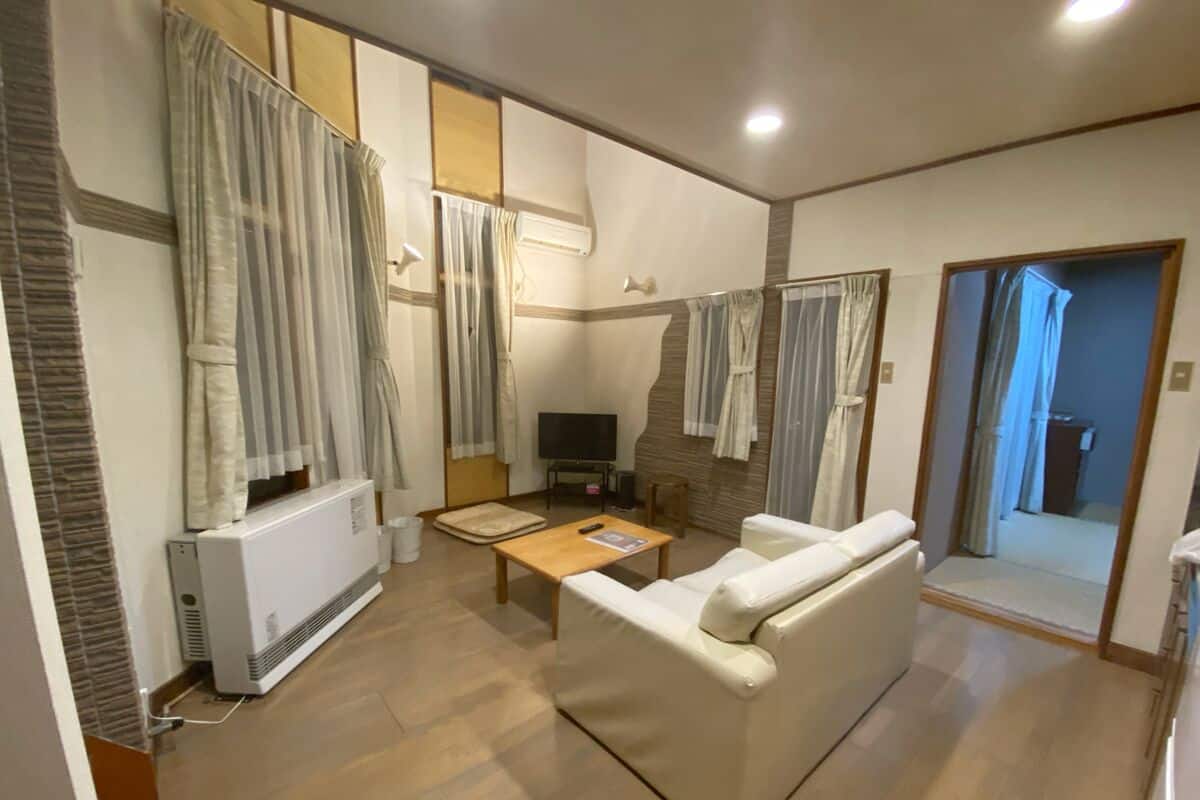 A living room with a sofa, a coffee table, a TV, and a radiator.