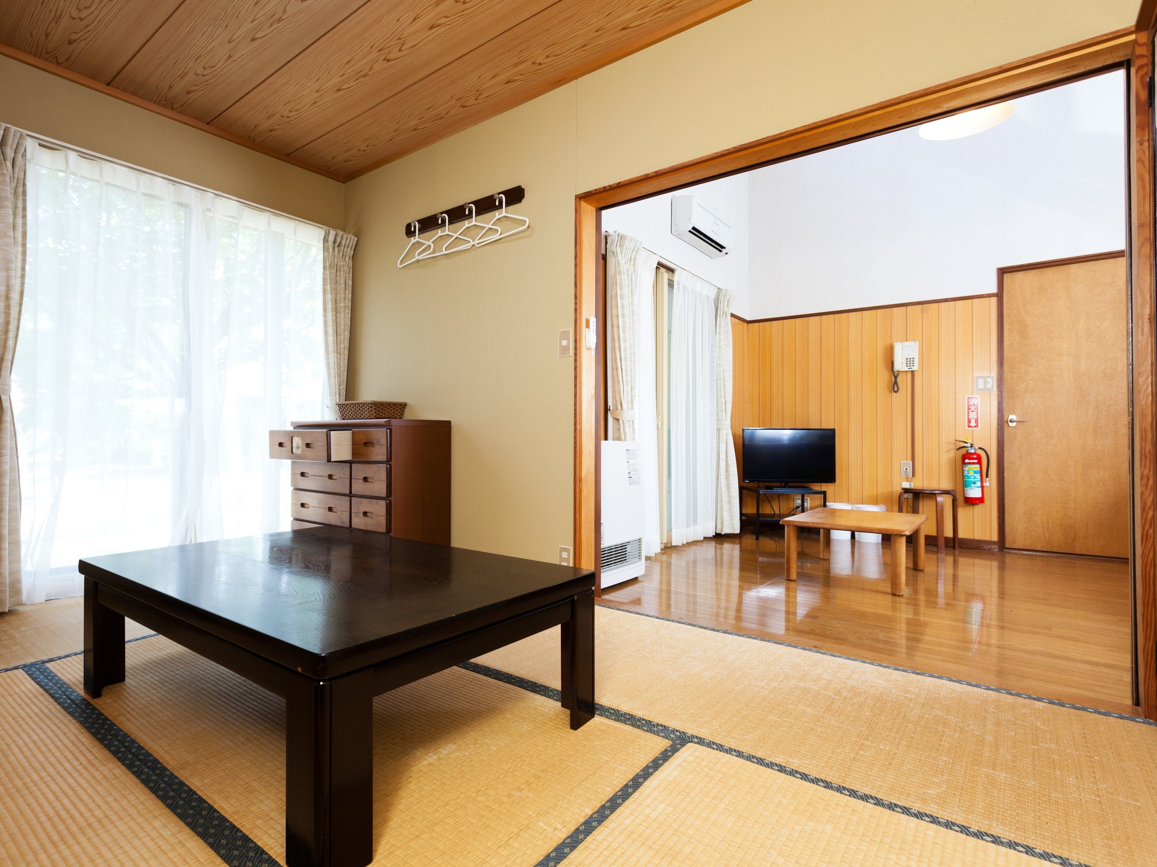 A room with a wooden table, a TV, and a fire extinguisher.