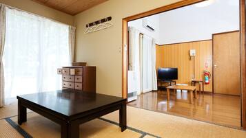 A room with a wooden table, a TV, and a fire extinguisher.