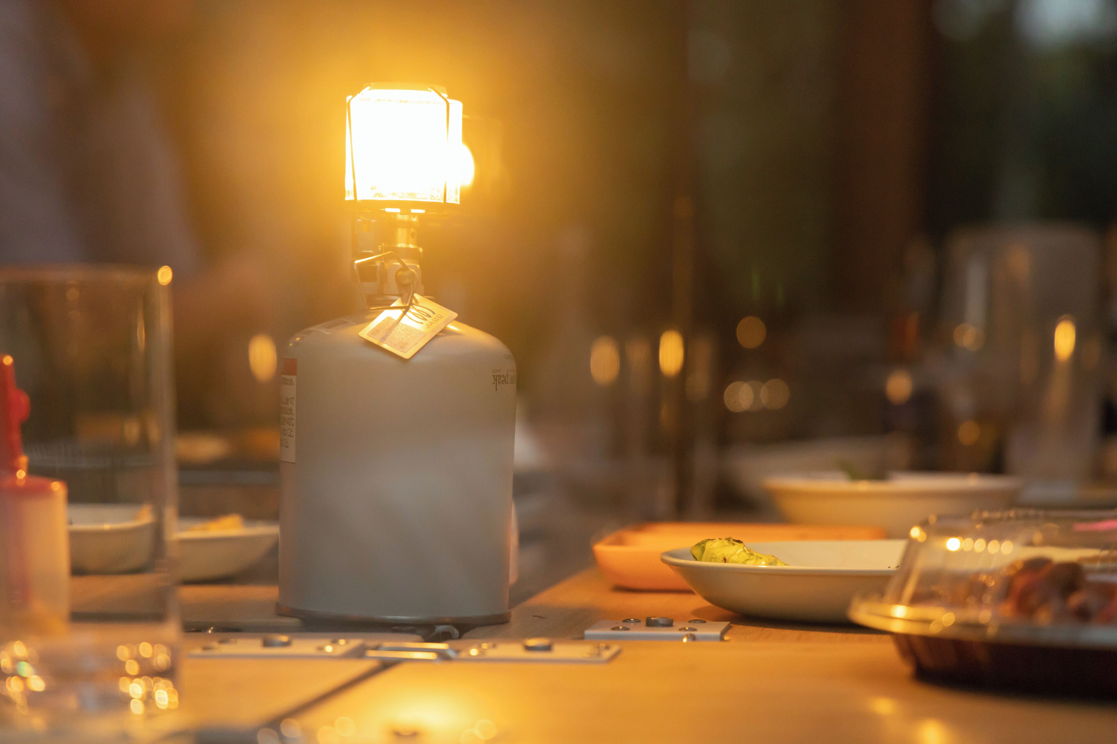 Una mesa con una botella de licor, vasos y un bol de comida.