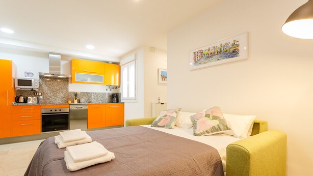 Un dormitorio con cama, almohadas y un sillón verde.