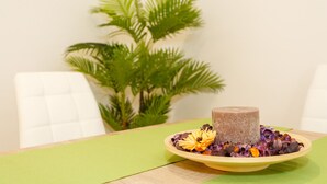 A table with a green placemat, a round yellow plate with a cylindrical object and purple and yellow flowers, and a white chair. - La Sorpresa del GENOVES by Cadiz4Rentals (Cádiz)
