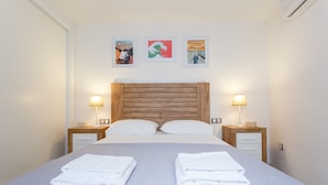 A neatly made bed with two pillows, two bedside tables with lamps, and three framed artworks on the wall. - La Sorpresa del GENOVES by Cadiz4Rentals (Cádiz)